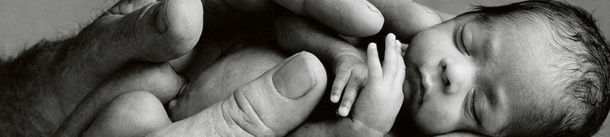 Afbeelding van een vroeggeboren baby in de handen van haar vader. Strong Babies is een goed doel dat zich inzet om vroeggeboorte tegen te gaan. Steun en help meer vroeggeboren baby's overleven